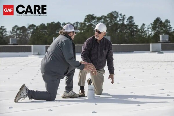 Image of two roofers on a roof inspecting tpo membranes