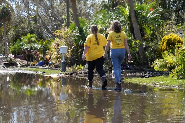 Two community helpers wading through storm water.