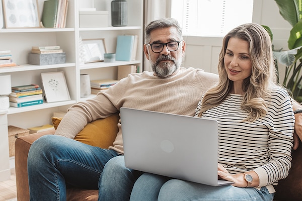 A seated homeowner couple browses GAF’s website for roofing contractors on a laptop.