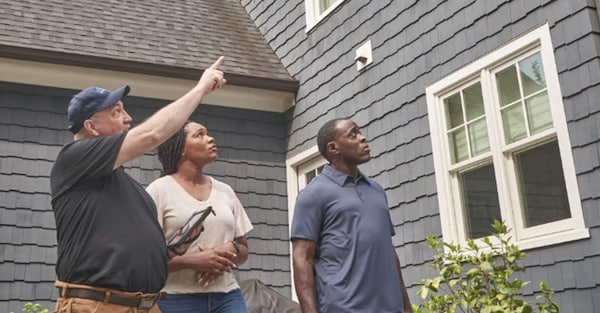 GAF certified contractor outside house with homeowners looking at roof damge