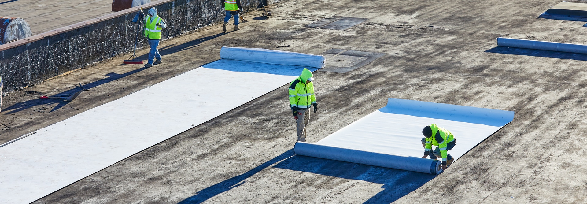 Contractors installing EverGuard® Fleece-Back single-ply membrane on a flat commercial rooftop.