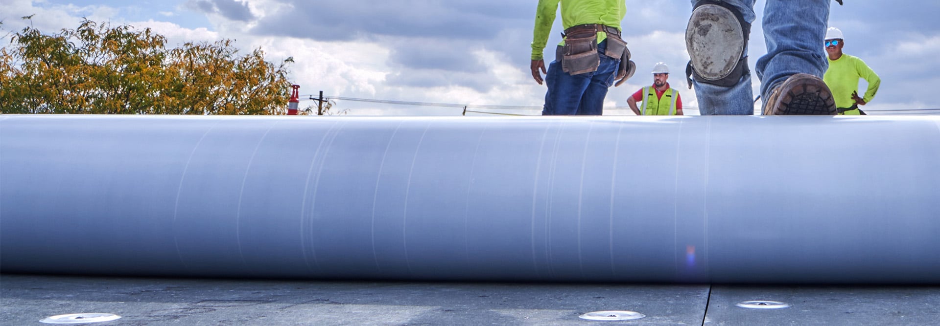 commercial roofing contractors on flat roof with membrane roll