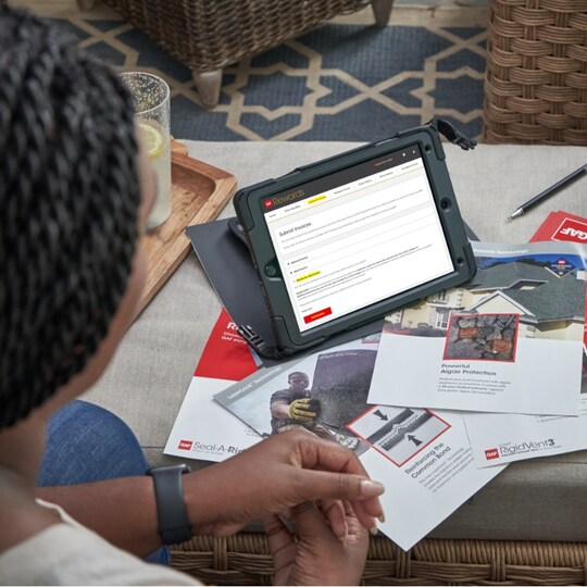 Man with tablet reviewing GAF Rewards materials for roof suppliers