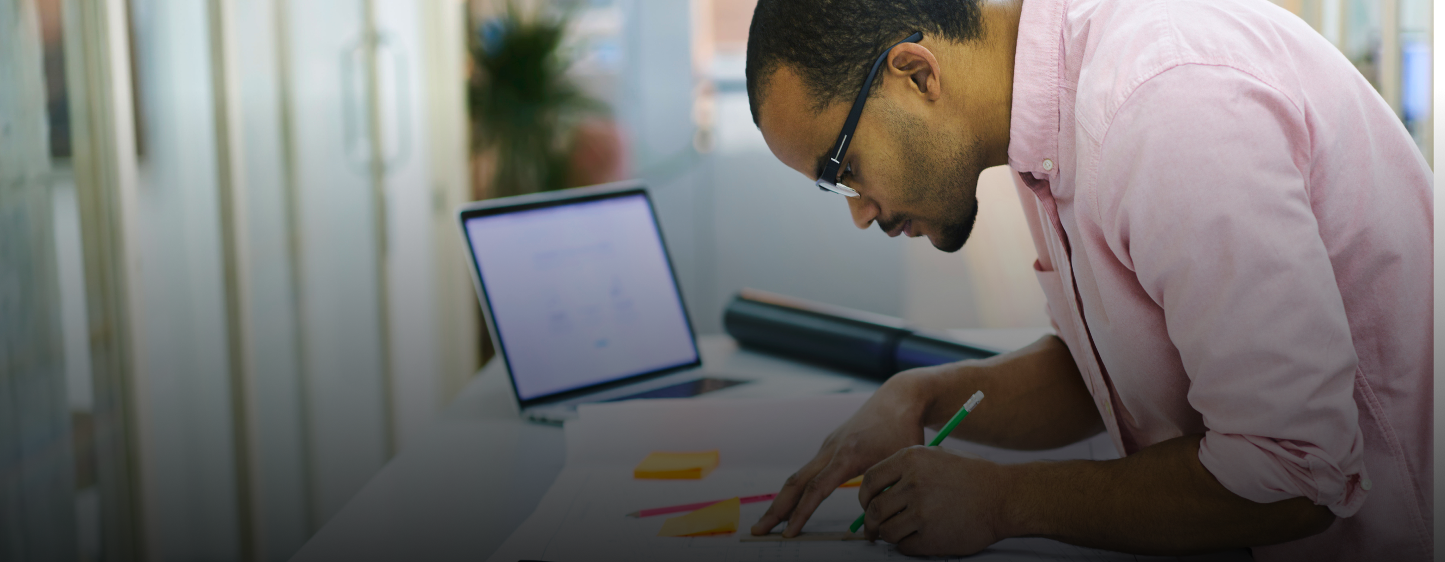 Architect reviewing roofing specification documents near open laptop