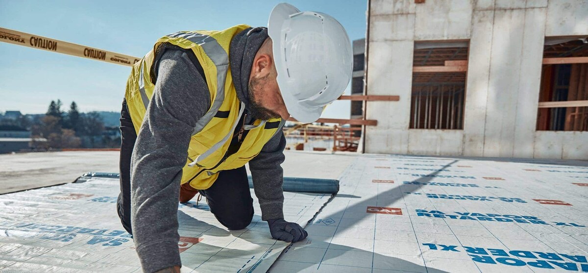 Close-up of contractor installing GAF SA Vapor Retarder XL on a flat roof